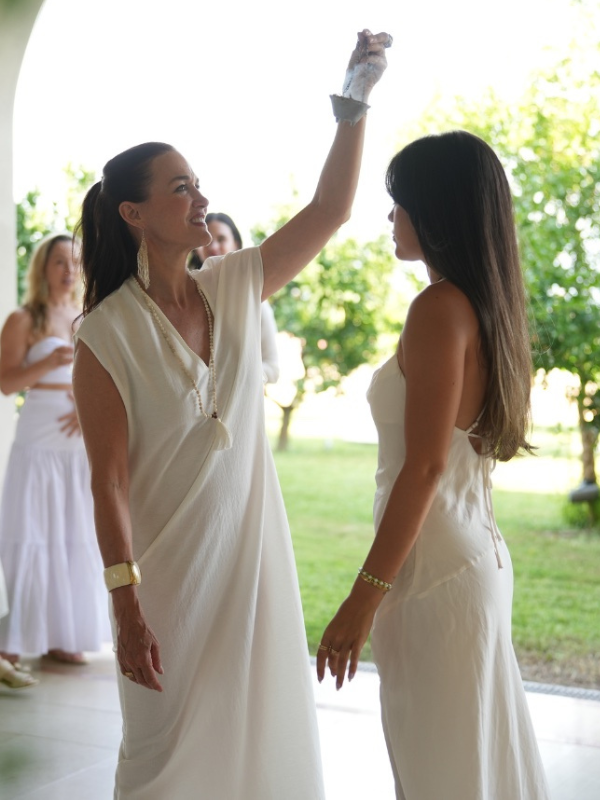 Maria Marshall welcomes a woman in a white dress with a sage blessing